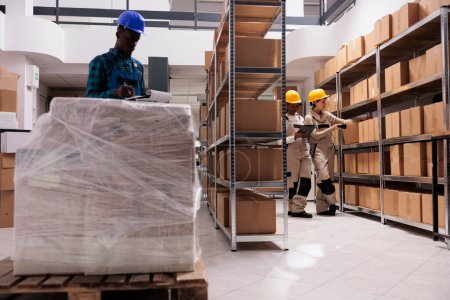 Photo for Delivery service storage workers managing parcel receiving and scanning boxes. Caucasian and african american warehouse colleagues using barcode scanner and checking freight documents before shipping - Royalty Free Image