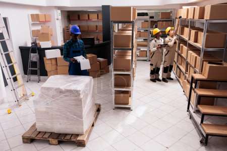 Photo for Industrial warehouse coworkers doing freight inventory, managing big parcel delivery. Storehouse employees making cargo transportation registration and scanning cardboard boxes barcodes - Royalty Free Image