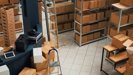 Foto de Empty warehouse with stacks of cardboard packages, small business concept with shelves and racks of merchandise. Product packed in boxes used for shipment and delivery, storage room. - Imagen libre de derechos
