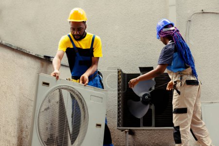 Foto de Técnicos eficientes afroamericanos desmontando el panel del sistema de hvac con técnicas y equipos de la industria para reparar filtros de aire, fugas de refrigerante y bobinas de evaporador congeladas - Imagen libre de derechos