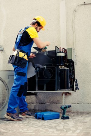 Électricien qualifié mandaté par le client pour le nettoyage et l'entretien courants annuels du système hvac, à l'aide d'une brosse à poussière douce pour enlever la couche accumulée de saleté et d'allergènes des composants électriques