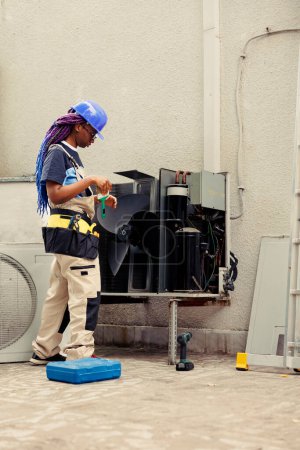 Photo for Specialist worker commissioned by home owner for air conditioner annual cleaning and maintenance, removing built up layer of dirt and dust from internal parts to prevent compressor damage - Royalty Free Image
