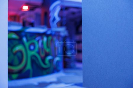 Foto de Lugar desolado iluminado por luces azules de neón, graffiti que brillan en la oscuridad y se ven espeluznantes. Edificio que se desmorona con el arte de la pintura en aerosol y luces brillantes fluorescentes, espacio vacío descuidado. - Imagen libre de derechos