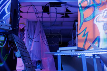 Photo for Demolished structure with neon lights turned into chaos, abandoned urban building glowing in the darkness of deserted warehouse. Neglected space with fluorescent purple glowy light. - Royalty Free Image