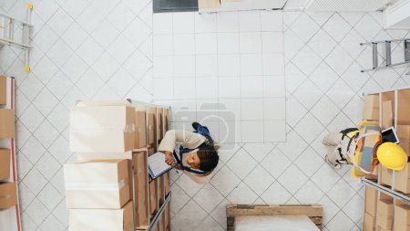 Photo for African american colleagues organizing stock on racks, planning order distribution for retail store management. Young employees working with merchandise in boxes or containers. Drone view. - Royalty Free Image