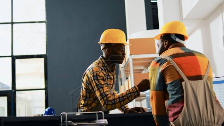 Photo for Young depot workers doing fist bump sign in storehouse, greeting each other at work. Team of people working in packs on racks and shelves, boxes of merchandise. Handheld shot. - Royalty Free Image