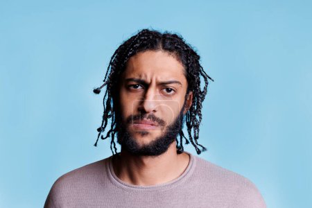 Photo for Arab confused man frowning eyebrows and looking at camera. Young adult arabian brunette person with braided hairstyle with unsure facial expression close up studio portrait - Royalty Free Image