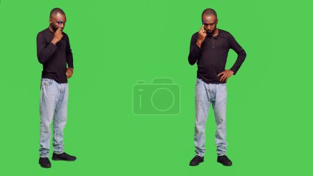 Photo for Pensive young man thinking about right decision in studio, feeling thoughtful over full body green screen. Male model brainstorming new ideas on camera, optimistic person in jeans. - Royalty Free Image