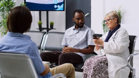 Photo for Senior medic showing antibiotic bottle to african american patient, explaining medical expertise during checkup visit in hospital reception. Doctor discussing health care treatment with sick man - Royalty Free Image
