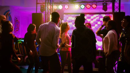 Téléchargez les photos : Danseurs cool montrant des mouvements de danse sur des rythmes funky, s'amuser avec les gens à la réunion sociale dans la discothèque. Groupe de personnes appréciant la fête sur la piste de danse, célébration. Coup de main. - en image libre de droit