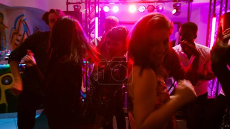 Téléchargez les photos : POV d'adultes heureux profitant de fête disco au club, s'amusant ensemble sur la musique électronique moderne. Amis dansant et faisant la fête dans la discothèque, sautant sous les lumières de la scène. Coup de main. - en image libre de droit