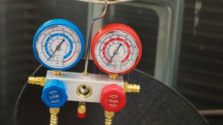 Photo for Close up shot of pressure measurement device used for checking condenser freon pressure. Set of manifold indicators showing high or low refrigerant levels in outdoor air conditioner - Royalty Free Image