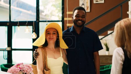 Photo for Guests waiting to do check in at tropical hotel front desk, arriving for summertime holiday honeymoon trip. Couple asking receptionist about booking accommodation at exotic ocean resort. - Royalty Free Image