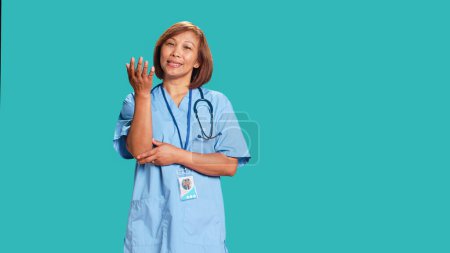 Photo for Licensed nurse offering pessimistic feedback to patient inquiry. Puzzled healthcare professional doing doubting gesturing while at work, isolated over blue studio background - Royalty Free Image