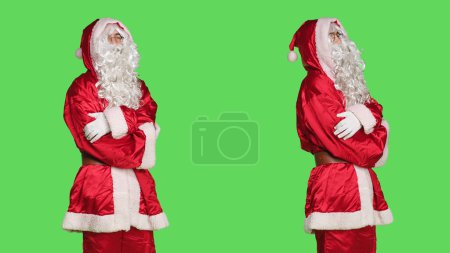 Photo for Man dressed in santa claus costume with fluffy white beard, stands against greenscreen backdrop. Character cosplay ready to spread winter holiday spirit, person portraying december happiness. - Royalty Free Image