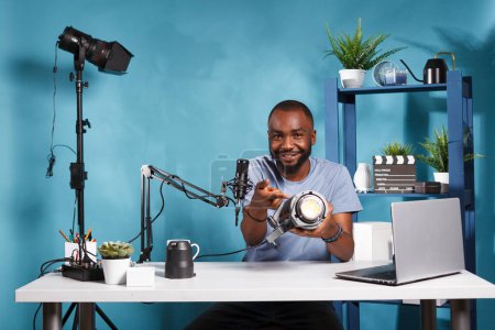 Photo for African american blogger testing and reviewing photography studio lightning equipment while live streaming. Photographer showing professional gear and recording video for online channel - Royalty Free Image
