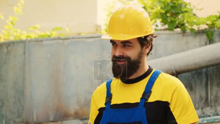 Photo for Cheerful technician commissioned for outside air conditioner annual maintenance, writing report on clipboard. Skilled smiling mechanic doing hvac system inspection, looking for faulty components - Royalty Free Image
