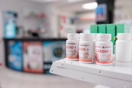 Foto de Selective focus of pills packages standing on shelves in empty pharmacy store, prepared for clients to buy. Drugstore space filled with pharmaceutical products and supplement boxes - Imagen libre de derechos