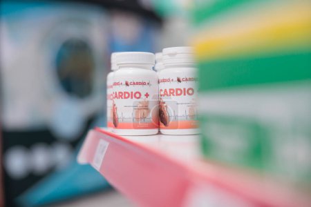 Foto de Drugstore shelves fiiled with cardiology bottle pills ready for clients to come and buy during medical visit. Pharmacy also carried a variety of other products, such as bandages and cold medicine. - Imagen libre de derechos