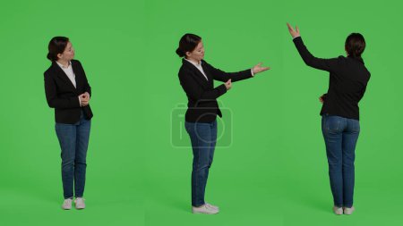 Photo for Caucasian businesswoman advertising presentation sideways, doing advertisement over full body greenscreen backdrop. Office worker showing ad icon and example in studio, presenting. - Royalty Free Image
