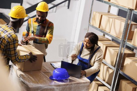 Photo for Warehouse manager checking orders list and coordinating parcels packing process. African american woman supervisor with laptop controlling freight cardboard boxes sealing and dispatching - Royalty Free Image