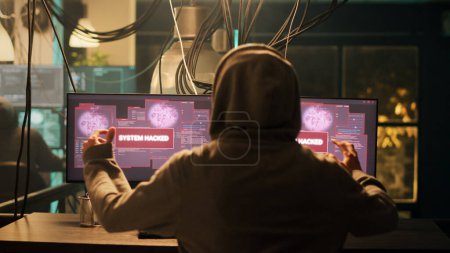 Male thief enjoying cybercrime achievement at night, breaking into security server to steal information. Young spy planning espionage and hacktivism, applauding and clapping hands.