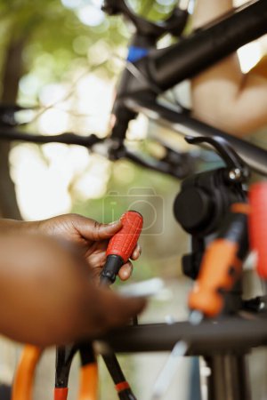 Téléchargez les photos : Plan détaillé d'une paire de mains afro-américaines tenant un tournevis de la boîte à outils pour l'entretien du vélo. Personne qualifiée examinant et arrangeant des outils spécialisés. - en image libre de droit