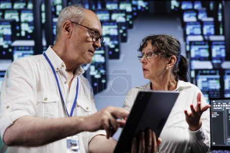 Foto de Los militares ancianos ejecutan análisis en supercomputadoras que ayudan a las empresas a administrar bases de datos, alojar sitios web y almacenar archivos. Meticulosos reparadores que auditan la electrónica de granja de servidores de alta tecnología - Imagen libre de derechos
