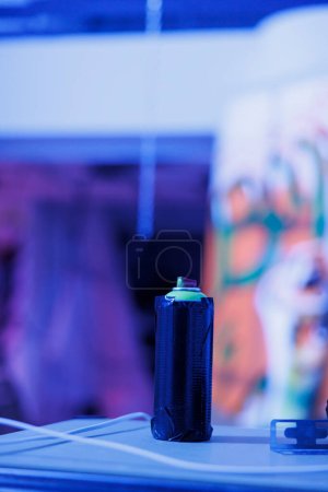 Foto de Aerosoles botellas utilizadas para el arte del graffiti en paredes descuidadas, latas de pintura en aerosol en almacén desierto con luces brillantes púrpura. Edificio vacío dañado con luces fluorescentes de neón. De cerca.. - Imagen libre de derechos