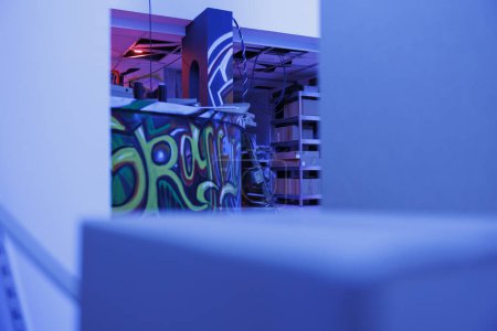 Foto de Lugar abandonado iluminado por luces brillantes púrpura, graffiti brillando en la oscuridad buscando gruñón. Edificio abandonado con pintura en aerosol y luz fluorescente de neón, espacio vacío en ruinas. - Imagen libre de derechos