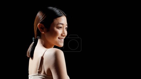 Photo for Beautiful lady applying anti aging cream on cheeks to advertise beauty routine, advertising skincare products in studio. Positive luminous woman promoting self acceptance and bodycare. - Royalty Free Image