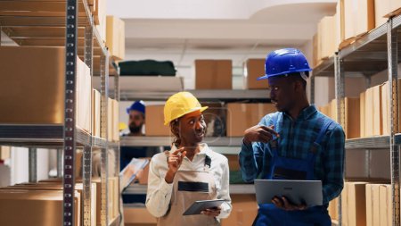 Photo for African american team counting warehouse goods on racks and planning order shipment, man and woman analyzing list of merchandise in storage room. Cargo logistics and inventory. - Royalty Free Image