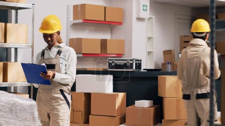 Photo for Team of women talking about package delivery service in storage room, examining stock in cardboard boxes. Diverse people checking merchandise and products in warehouse. Tripod shot. - Royalty Free Image