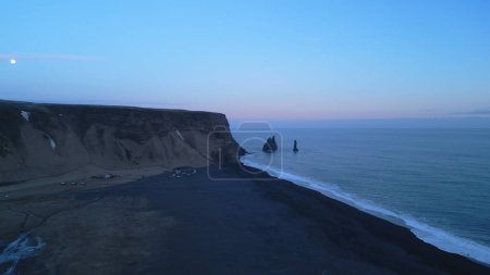 Photo for Drone shot of reynisfjara beach scenery on atlantic shore, spectacular black sand beach in iceland. Massive hills reynisfjall mountain creating fantastic skyline and landscape. Slow motion. - Royalty Free Image
