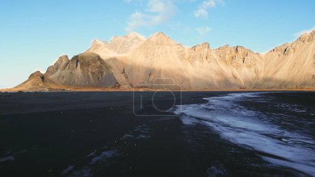 Téléchargez les photos : Vue aérienne des montagnes du vestrahorn en iceland, de la plage de Stokksnes et de la péninsule formant un beau paysage nordique. Paysage spectaculaire avec plage de sable noir, nature glacée. Mouvement lent. - en image libre de droit