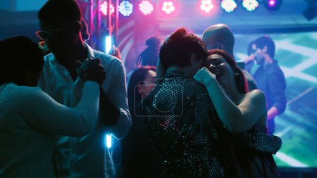 Photo for Dance partners waltzing on dance floor, attending party with friends at discotheque. Young people dancing in pairs on slow romantic music, showing off dance moves at club. Tripod shot. - Royalty Free Image