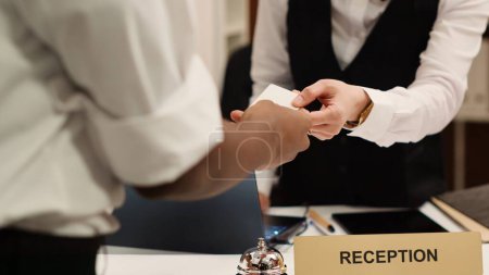 Photo for Close up of receptionist handing card key to elegant african american tourist during check in process. Business travelling guest ready to enjoy hotel stay after receiving room access - Royalty Free Image