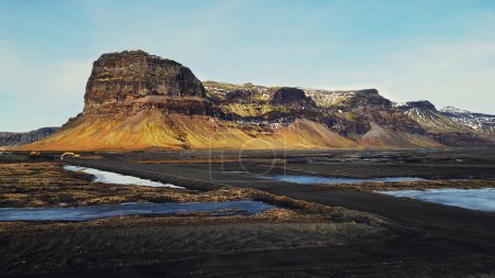 Téléchargez les photos : Drone shot de montagne majestueuse dans le pays de glace, spectaculaire bord de route et champs enneigés. Collines massives islandaises et terres gelées brunes dans des paysages scandinaves. Mouvement lent. - en image libre de droit