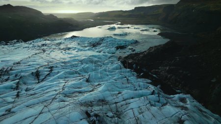 Téléchargez les photos : Vue aérienne d'une énorme glace sur un lac gelé, de massifs rochers glacés flottant autour des eaux de la péninsule. Paysages nordiques polaires spectaculaires avec calotte glaciaire du glacier vatnajokull, montagnes enneigées. Mouvement lent. - en image libre de droit