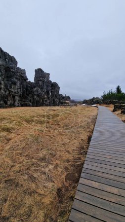 Foto de Paseo en parque nacional icelandés, campos congelados en valle con acantilados rocosos formados por piedra maciza. Cosa escandinava formación rocosa vellir en Islandia, fantástico entorno natural. - Imagen libre de derechos