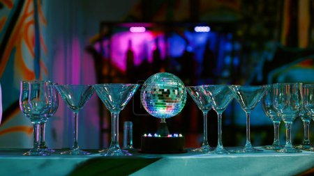 Empty club bar with glasses and drinks, alcoholic beverage in the club used for partying and entertainment. Modern discotheque with alcohol and dance floor with lights. Close up.