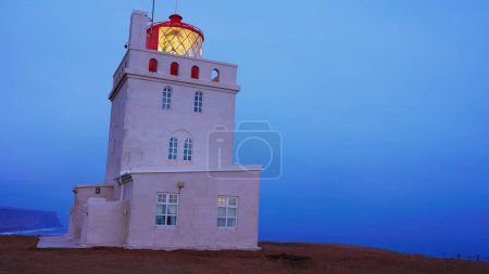 Photo for Dyrholaey lighthouse on arctic coastline, beautiful old building with navigation light on shore. Tower structure used for guidance on icelandic cliff, vik city landscapes. Handheld shot. - Royalty Free Image