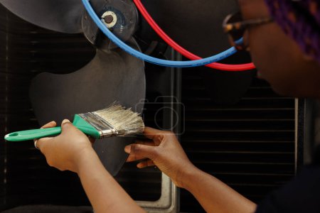 Photo for Seasoned mechanic removing layer of dirt from blower fan to prevent damaging of ventilation system. Adept repairman cleaning hvac system parts to stop risk of overheating, close up - Royalty Free Image
