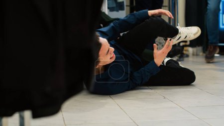 Photo for Dangerous black friday behaviour. Crowd pushing each other in clothing store while persons fall on the floor. Reckless crowd of shoppers hurting asian clients, aggressive people. Handheld shot. - Royalty Free Image