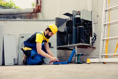 Photo for Skilled repairman starting annual routine maintenance on outdoor air conditioner. Qualified worker preparing toolkit for checking refrigerant leaks responsible for reduced cooling efficiency - Royalty Free Image