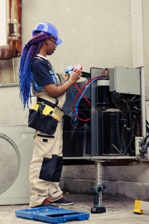 Photo for Qualified engineer commissioned by home owner for annual hvac system maintenance, assembling professional manometers. Competent mechanic checking freon pressure in air conditioning system - Royalty Free Image