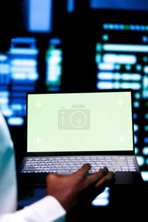Photo for Expert examining server cabinets performance trends using green screen device. Serviceman uses chroma key laptop to pinpoint data center operational issues arising due to insufficient memory, close up - Royalty Free Image