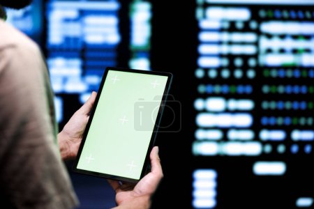 Foto de Administrador que usa la tableta de pantalla verde para hacer mantenimiento en servidores de juegos dedicados de alto ancho de banda utilizados para acomodar el tráfico entrante de usuarios en línea que juegan desde ubicaciones mundiales - Imagen libre de derechos