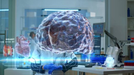 Foto de Mujer con auriculares VR de alta tecnología mientras la científica monitorea sus ondas cerebrales en la pantalla, utilizando la visualización del holograma de realidad aumentada para mejorar la comprensión de la investigación de neurología de la mente humana - Imagen libre de derechos