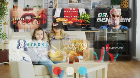 Photo for Mother and daughter watching TV using AR projector display, relaxing at home on cozy sofa while enjoying snacks and beverages. Smiling family scrolling through streaming services movies - Royalty Free Image